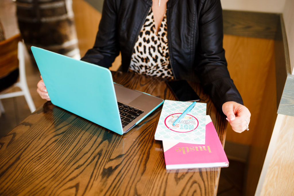 woman sitting at table with teal laptop