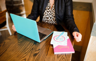 woman sitting at table with teal laptop