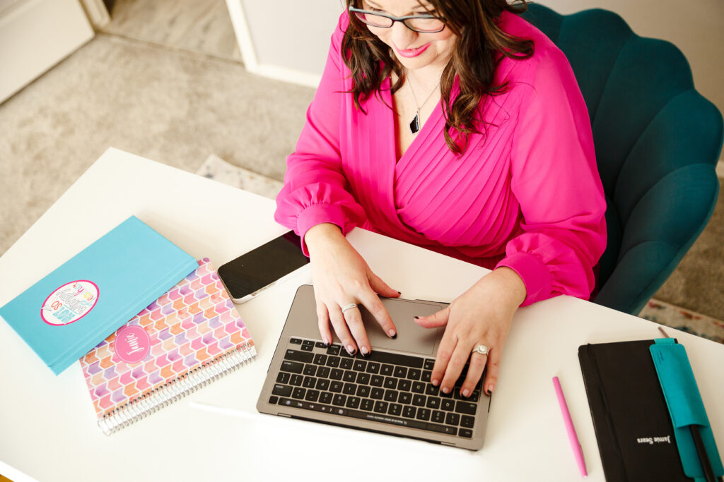 teacher sitting at desk writing emails on laptop